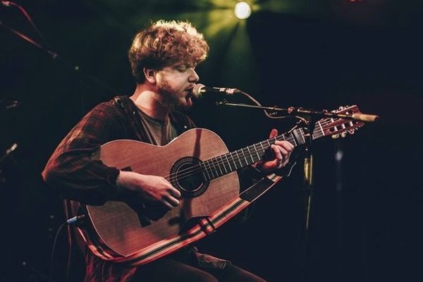 Thomas Ashby performing onstage with a guitar